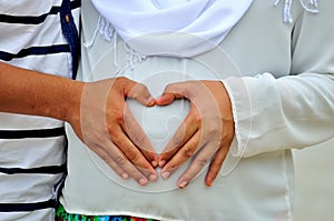 Hands in a heart shape on baby bump