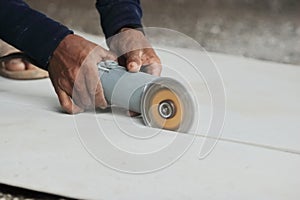 Hands of heavy industry worker with angle grinder cutting concrete.