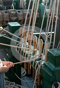 Hands help tie lines from sails on a tall ship