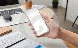 hands hold cell phone with blank white screen, for displaying app interface or website design. Person in office environment hold