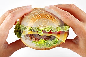 Hands hold a cheeseburger