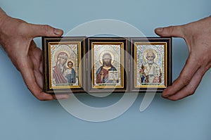 Hands hold the Christian icon of Christ, the mother of God and St. Nicholas the wonderworker, the patron saint of sailors and photo