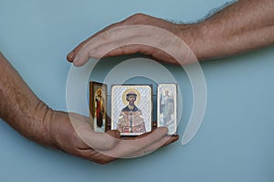 Hands hold the Christian icon of Dmitry Donskoy and the archangels Gabriel and Michael