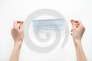 Hands hold a disposable protective mask on a white background