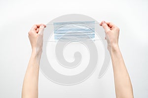 Hands hold a disposable protective mask on a white background