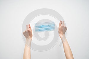 Hands hold a disposable protective mask on a white background
