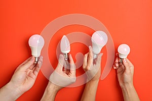 Hands hold energy saving bulbs on red background