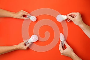 Hands hold energy saving bulbs on red background