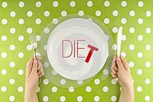 Hands hold flatware above dieting plate