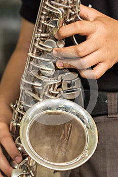 Hands hold a saxophone