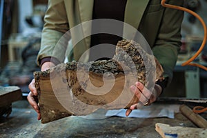 Hands hold a slab of burl wood with intricate grain, highlighting the natural artistry that woodworkers cherish and