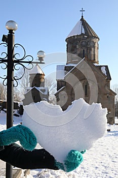 Hands hold snowy heart near Church in Sevanavank photo