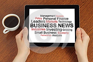 Hands hold tablet PC with tag cloud of business news