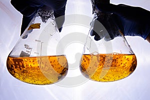 Hands hold two glass bowls with yellow bubble liquid