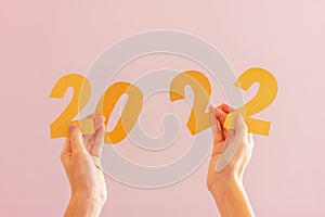 Hands hold yellow numbers 2022 from paper