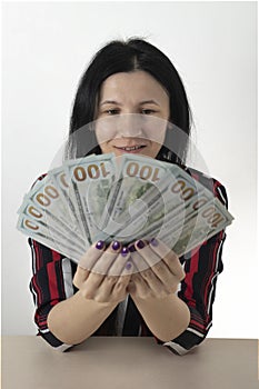 Hands are holding 100 dollar bills. Female hands holds a fan of dollars on a wooden table