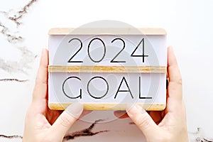 Hands holding 2024 goals wood box over marble background, banner, business new year, aim to success in business