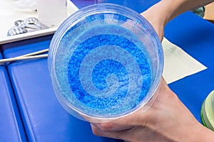 Hands holding beaker of blue chemical, Copper Sulphate Pentahydrate photo