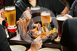 Hands holding beer glasses drinking together in the pub