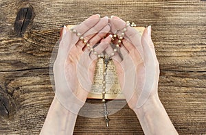 Hands holding the Bible and praying with a rosary