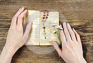 Hands holding the Bible and praying with a rosary