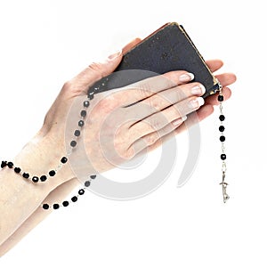 Hands holding the Bible and praying with a rosary