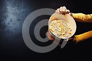 Hands holding big bucket of hot sweet and salty popcorn