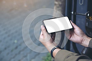 Hands holding black mobile phone with blank desktop screen horizontally