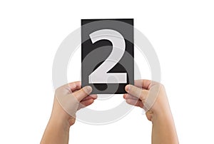 hands are holding a black paper card with number 2 isolated on white background