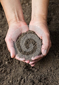 Hands holding black soil. Close-up