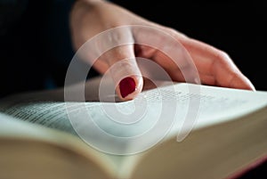 Hands holding a book that an elderly woman is reading using her fingers on the lines filled with words