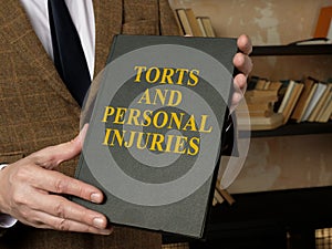 Hands holding a book Torts and Personal Injuries law book.