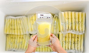 Hands holding Breast Milk Storage Bag in front of stocks in freezer