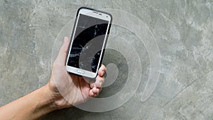 Hands holding broken moblie smart-phone focused on concrete wall