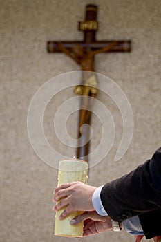 Hands holding candle with cross in background