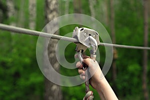 Hands holding carabiner on zip line