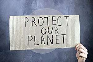 hands holding a cardboard poster with an inscription save our planet