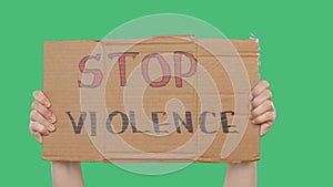 Hands holding cardboard with stop violence sign on green chromakey background. Hands showing inscription stop violence