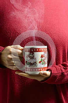Hands holding a christmas cup with a hot beverage