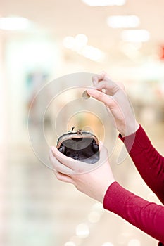 Hands holding coin and money pouch in mall