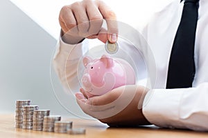 Hands holding coins placed in a piggy bank, Businessmen prepare a financial plan by accounting income - expenses for stable busine