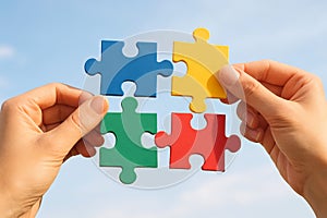 Hands holding colorful puzzle pieces against clear blue sky. concept of problem solving, teamwork, collaboration, connection