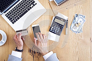 Hands holding credit card and paying bills on table