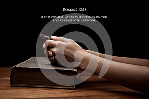 Hands holding a cross on holy Bible with verse
