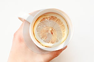 Hands holding cup of hot tea. Ginger tea with lemon. A Cup of tea is held by a woman's hand. Season of colds and infections.
