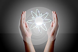Hands holding and cupping a glowing atom