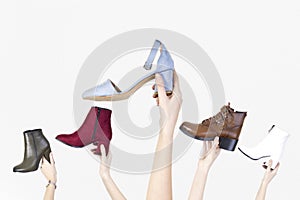 Hands holding different woman shoes on white isolated background.