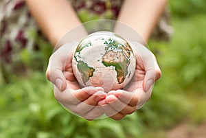 Hands holding earth globe on green grass background. Earth day concept. Saving the planet, environment. Created with generative Ai