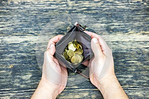 Hands holding an empty wallet with coins