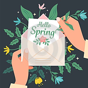 Hands holding an envelope with a greeting card Hello spring on a background of flowers.